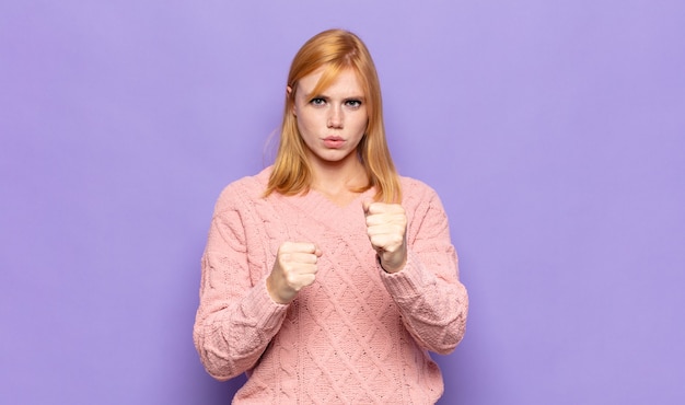 red head pretty woman looking confident, angry, strong and aggressive, with fists ready to fight in boxing position