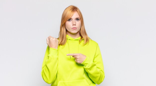 Red head pretty woman looking impatient and angry, pointing at watch, asking for punctuality