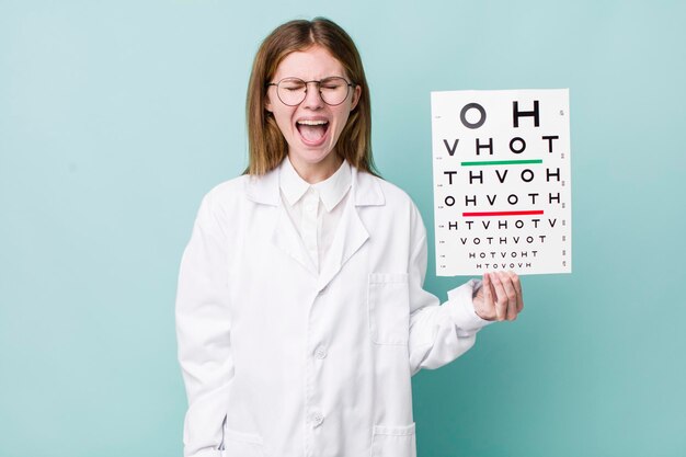 Red head pretty woman shouting aggressively looking very angry optical vision test concept