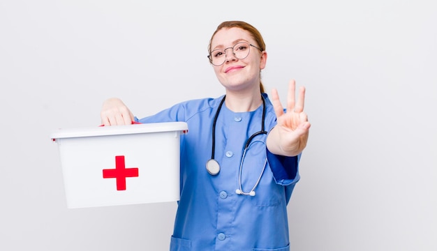 Red head pretty woman smiling and looking friendly showing number three nurse concept