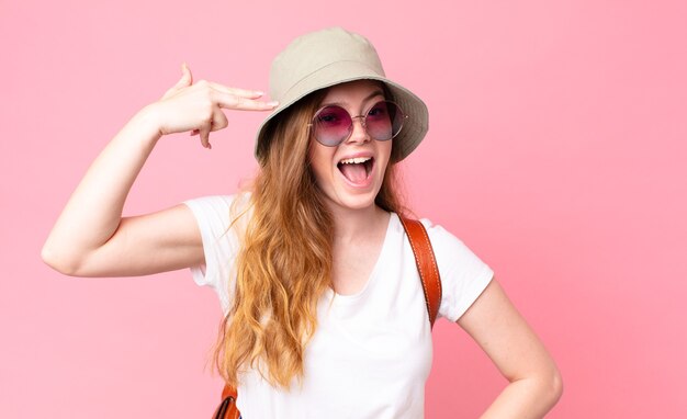 red head pretty woman tourist looking unhappy and stressed, suicide gesture making gun sign