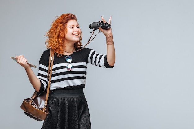 Red head tourist girl looks through binoculars