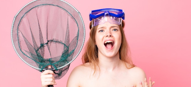 Red head woman looking desperate, frustrated and stressed with goggles an fishing net