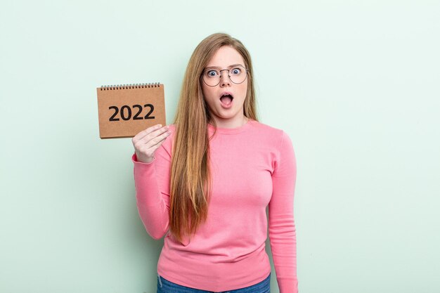 Red head woman looking very shocked or surprised agenda 2022 concept