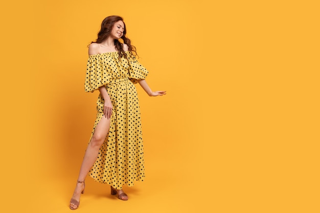 Red-head woman in yellow dress posing on yellow. Summer mood