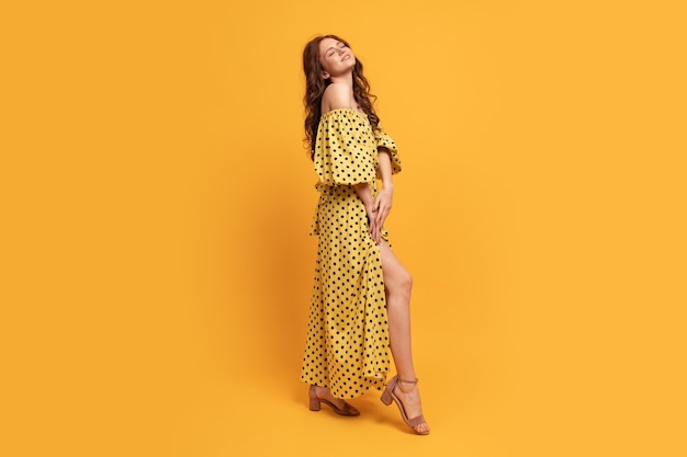 Red-head woman in yellow dress posing on yellow. Summer mood