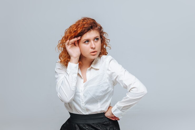 Photo red headed girl in white shirt thinks on light gray background