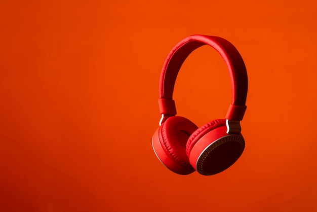 Red headphones on plain red background in studio