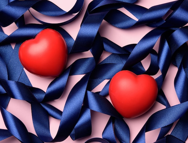 Red heart and blue silk curled ribbon on a pinkd surface, valentine's day, top view