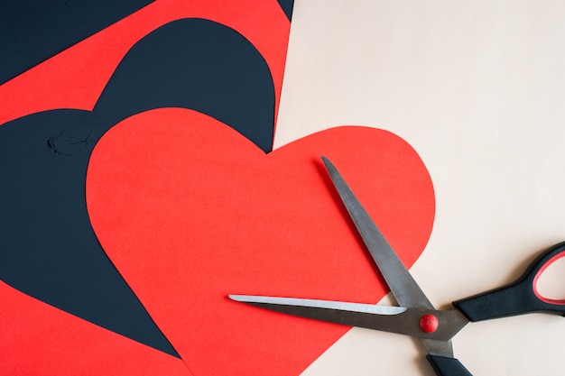 Red heart carved from paper sheet and scissors