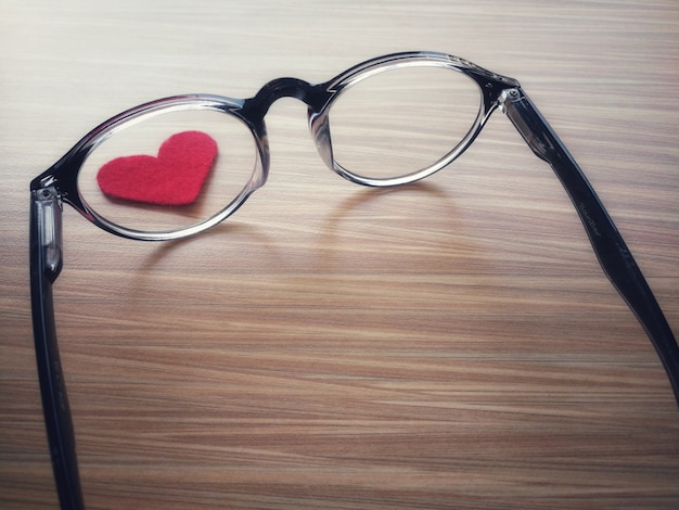 Red heart in the center of the glass.on brown wood.blurred and vintage tone background.