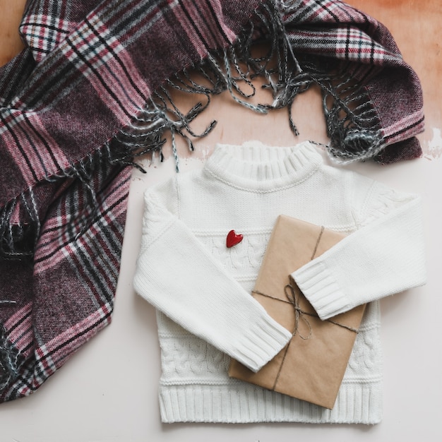 A red heart, gift and a white knitted sweater. top view, copy space