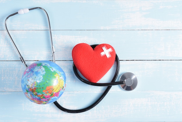 Red heart and globe on blue and white pastel wooden background. healthcare and medical concept.