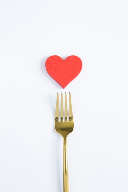 Photo red heart and gold fork on the white background. copy space.top view.