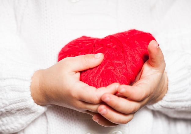 Foto cuore rosso nelle mani del ragazzino in camicetta bianca