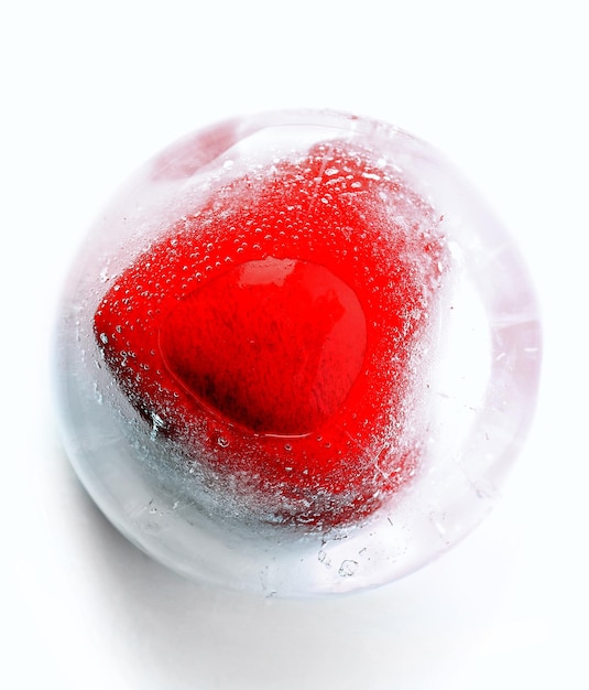 Red heart in ice cube isolated on white