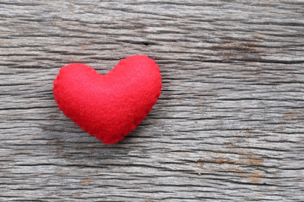 Red heart is placed on a wooden floor.