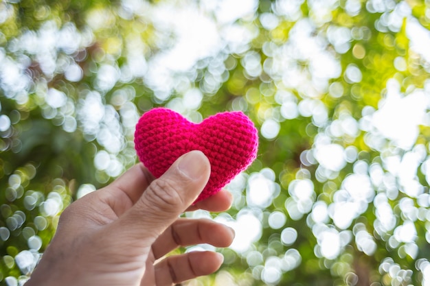 Red heart knitting in hand with nature background