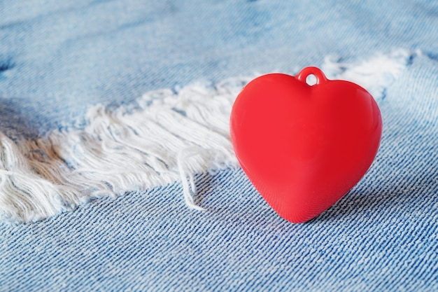 Red heart  laying on top of old and tear blue jeans. Valentine concept.