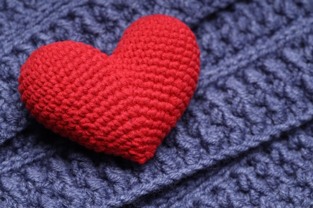 Red heart lies on a blue knitted napkin. Love concept. High quality photo