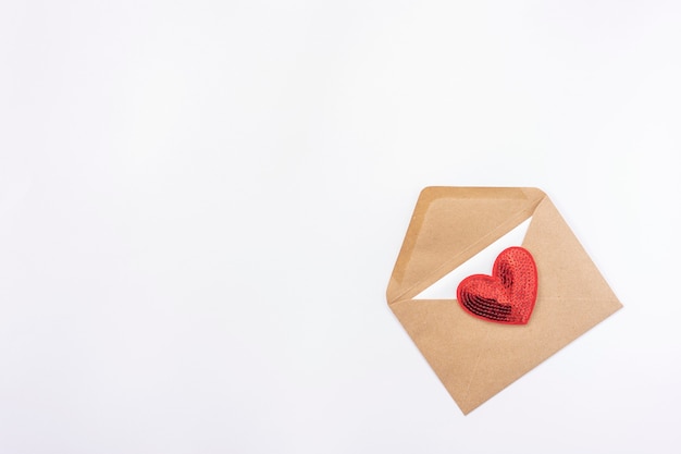 A red heart lies on a brown envelope for Valentines Day