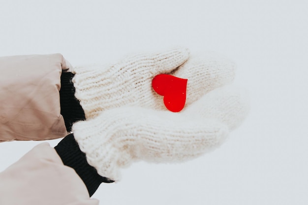 Red heart lies on the fresh mittens winter snow the woman dares in her palms a small red heart closeup