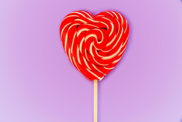 Red heart lollipop on purple background love and valentine day background