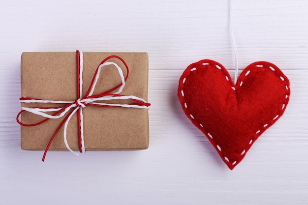 Red heart made of felt and handmade, on a white wooden table