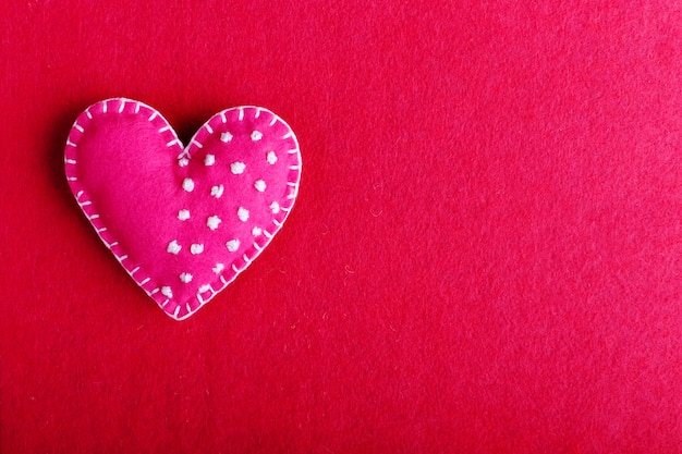 Red heart made of felt on a red background