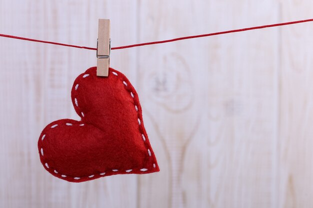 Red heart made of handmade felt hanging on a rope with a pin