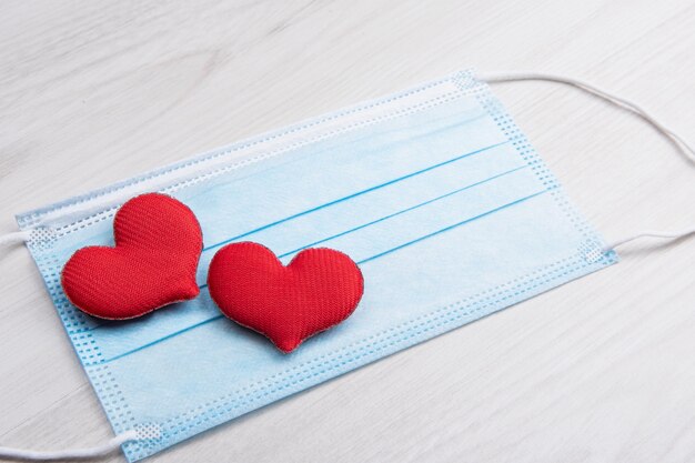 Red heart on medical face masks. Concept support, love, care and a thank you to the frontline essential and healthcare workers.Happy valentines day. Pandemic, quarantine coronavirus.Valentine's Day.