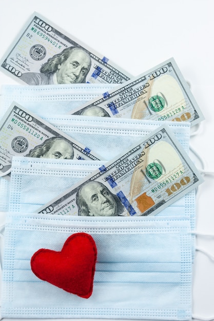 Red heart, medical masks and dollars. Financial crisis due to coronavirus. Expensive hospital services.