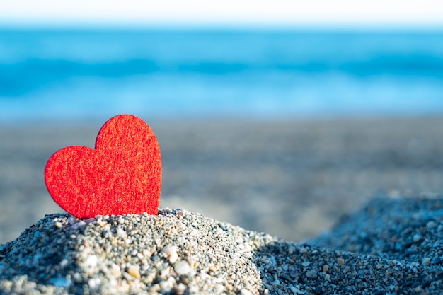 Photo red heart on a mountain of sand by the sea. concept of san valentine