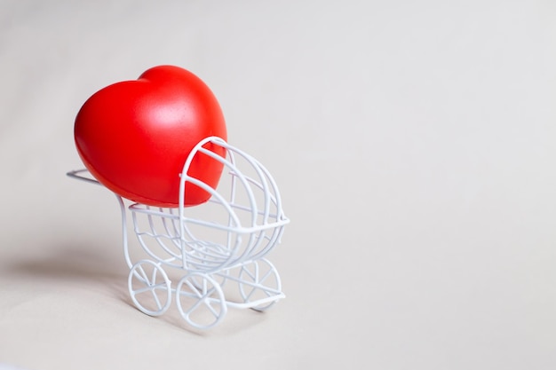 Red heart in the pram or carriage isolated on beige background