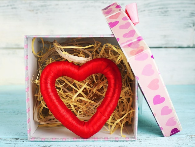 Red heart in present box on wooden table