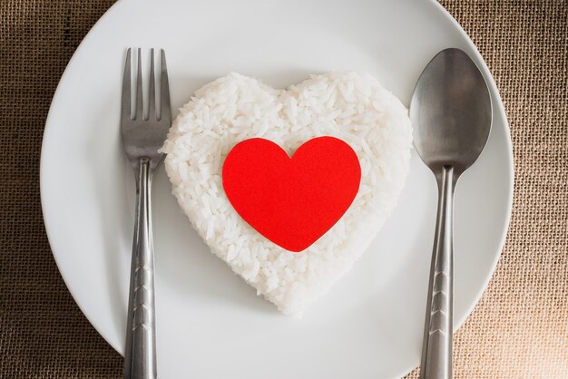 Photo red heart on rice heart shape on whiteplate