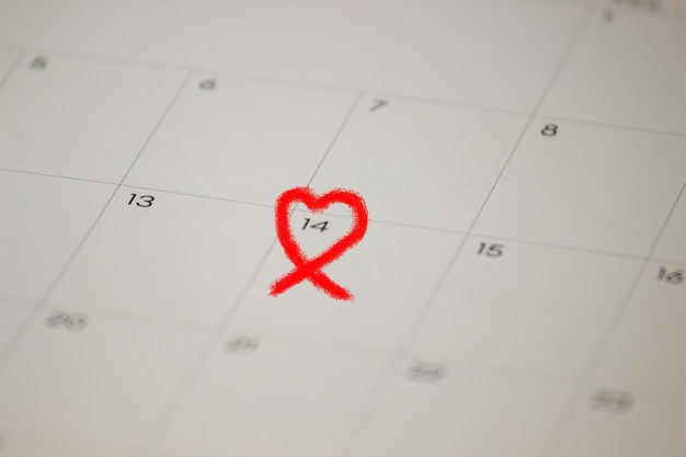 Foto la forma del cuore rosso è disegnata sul calendario per presentare il giorno di san valentino per amore e anniversario