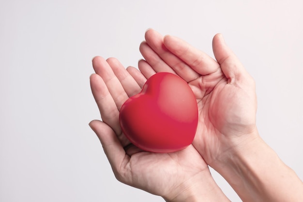 Red heart shape is in hands to give love and care as gift on valentine's day Symbol of love