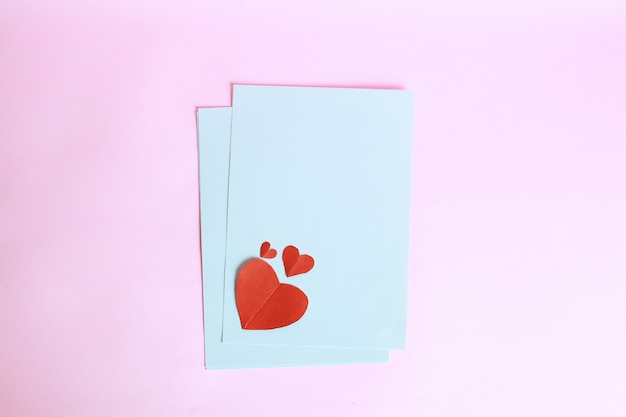 Red heart shape on white envelope paper isolated on pink background