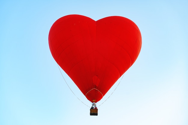 Red heart-shaped air balloon flying in the clear sky