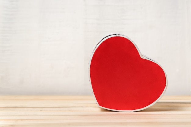 Red heart shaped box on the table. Side view. Space for text. Valentine's Day
