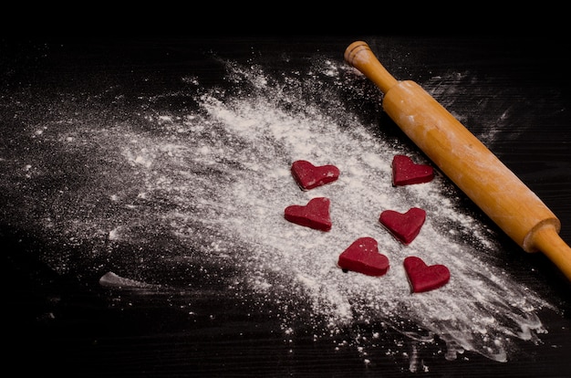 Red heart-shaped cookies on a flour, baking the day of Valentine's Day