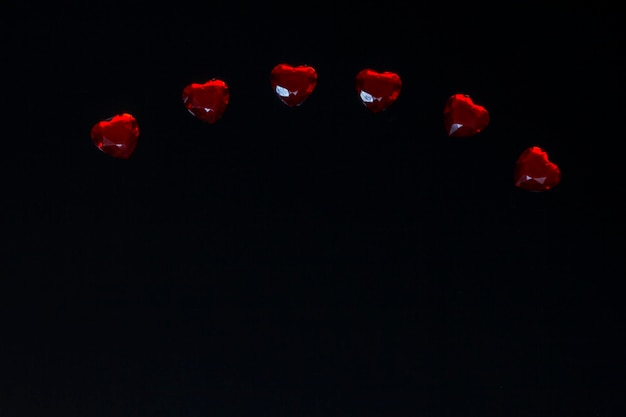 Red heart shaped gemstones on black background