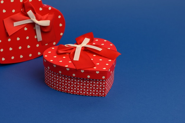 Red heart shaped gift box on blue wall, close up