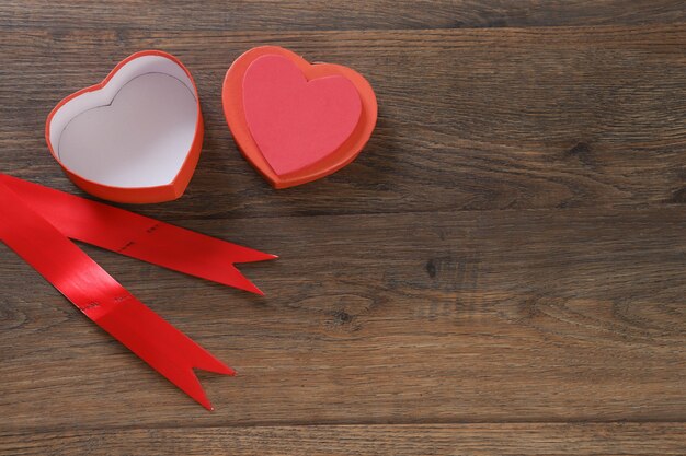 Red heart-shaped gift box on wooden table.