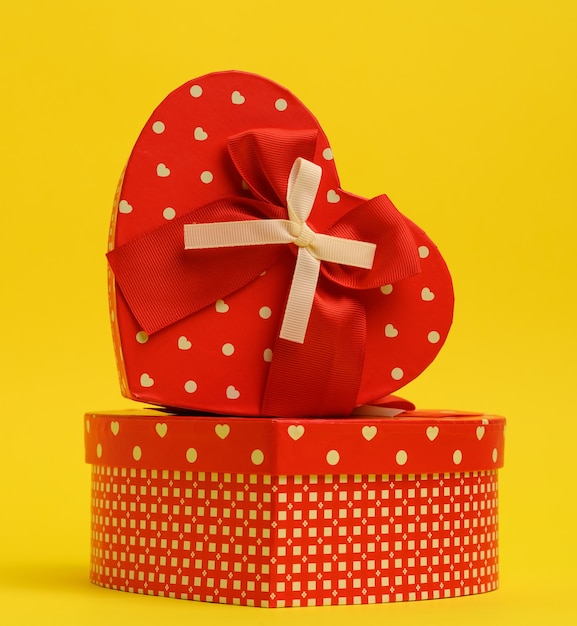 Photo red heart shaped gift box on a yellow wall, close up