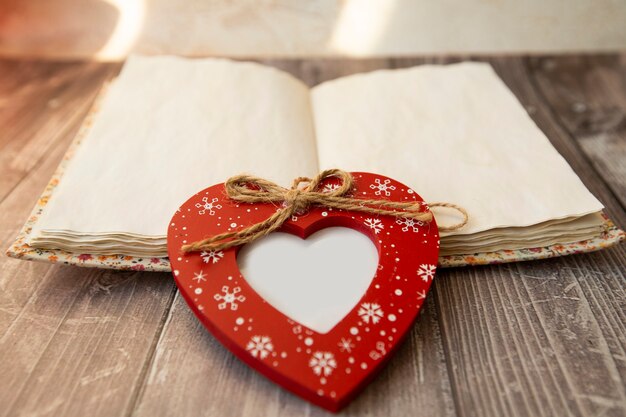 a red heart-shaped photo frame lies on notebook