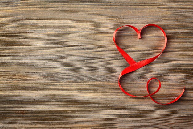 Red heart shaped ribbon on wooden background