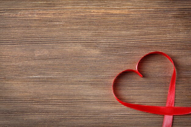 Red heart shaped ribbon on wooden background