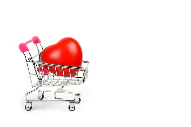 Il cuore rosso forma nel carrello su sfondo bianco il concetto di amore per lo shopping su valent